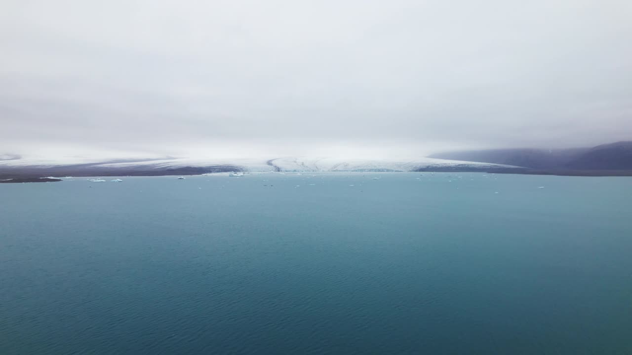 冰山散落在广阔的蓝色海洋和晴朗的天空的鸟瞰图视频素材