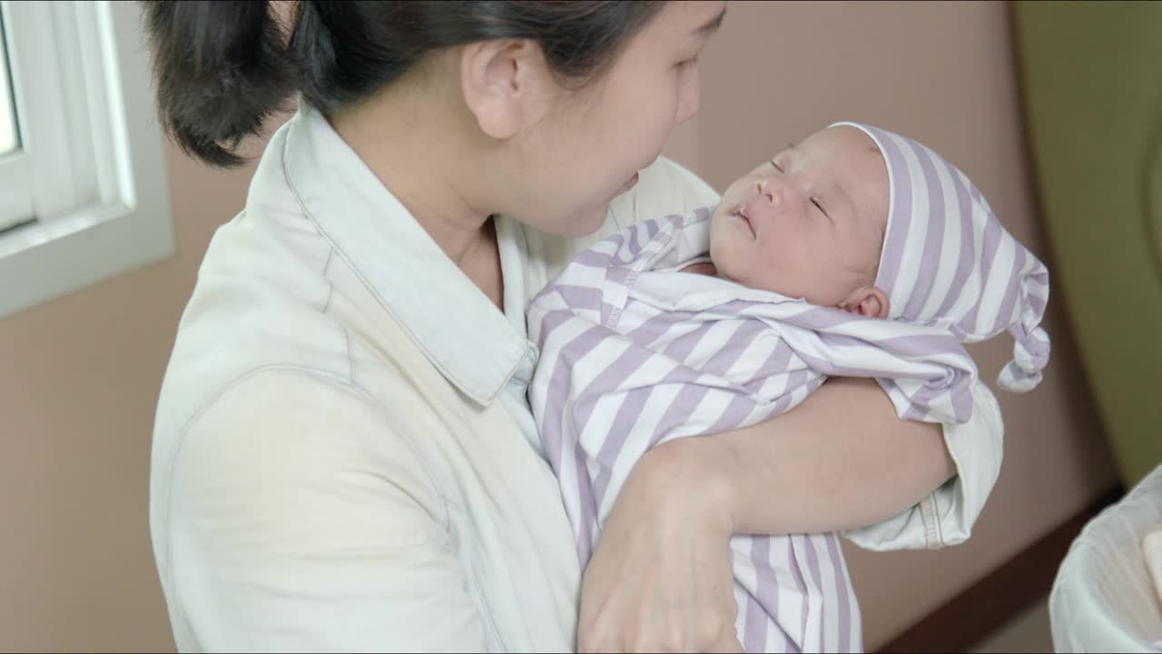 可爱的亚洲小女孩在妈妈的怀里睡着了。新生儿护理，父母，婴儿，生活，母性，母性，家庭爱和纽带概念。视频素材