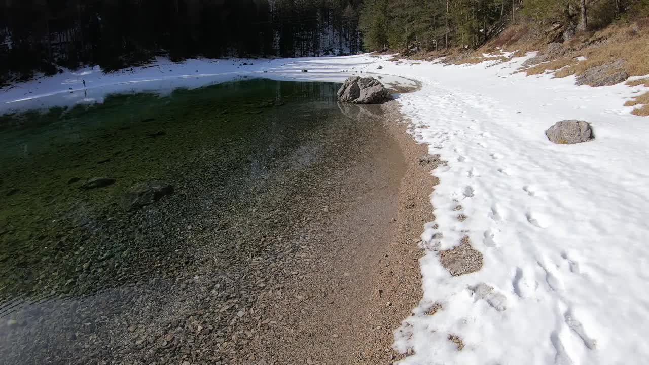 冬天，在奥地利宁静的绿湖岸边散步。湖被雪包围着。湖的四周有一片茂密的森林。清水。阳光明媚的一天。平静和冷静视频素材