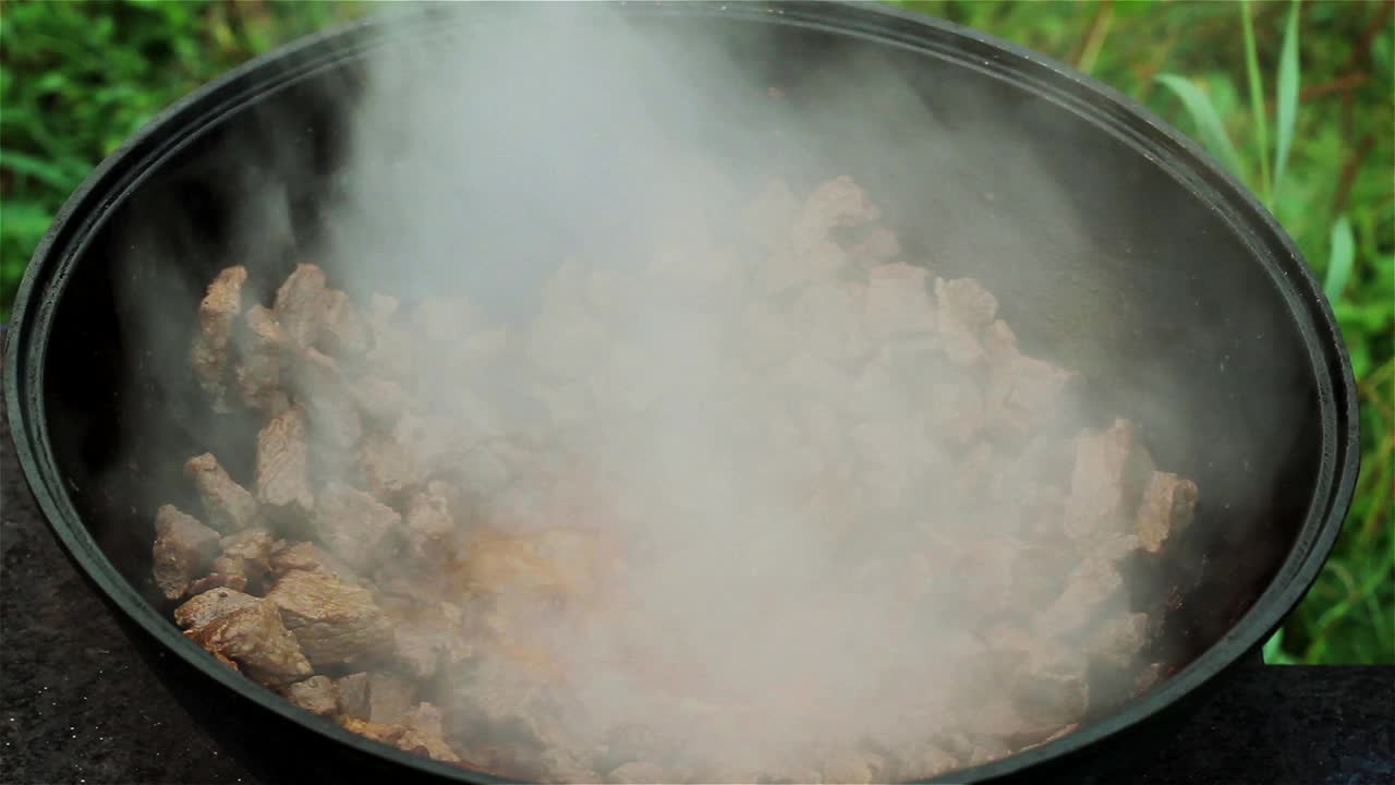 肉是在一个大的铸铁锅上在明火上炖的。将牛肉与木勺混合，将洋葱加入锅中。所有配料都在锅里混合视频下载