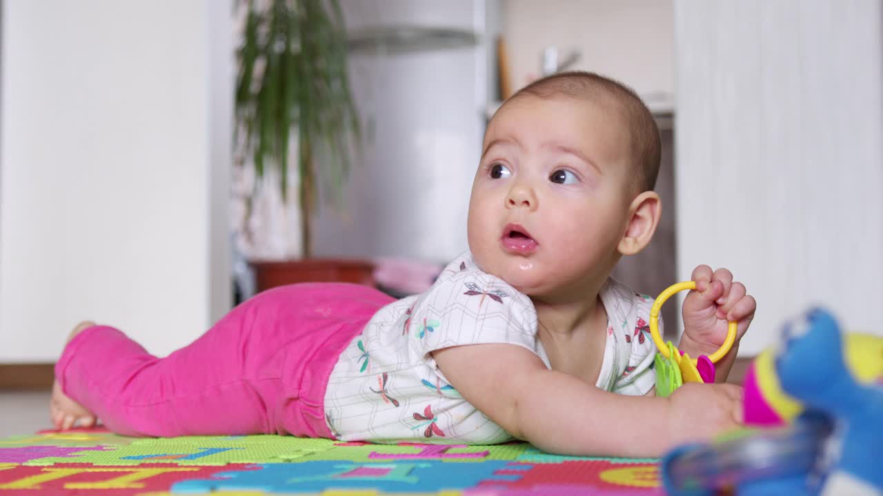 一个漂亮的新生婴儿的肖像，躺在他的肚子上，有趣地看着相机。视频素材