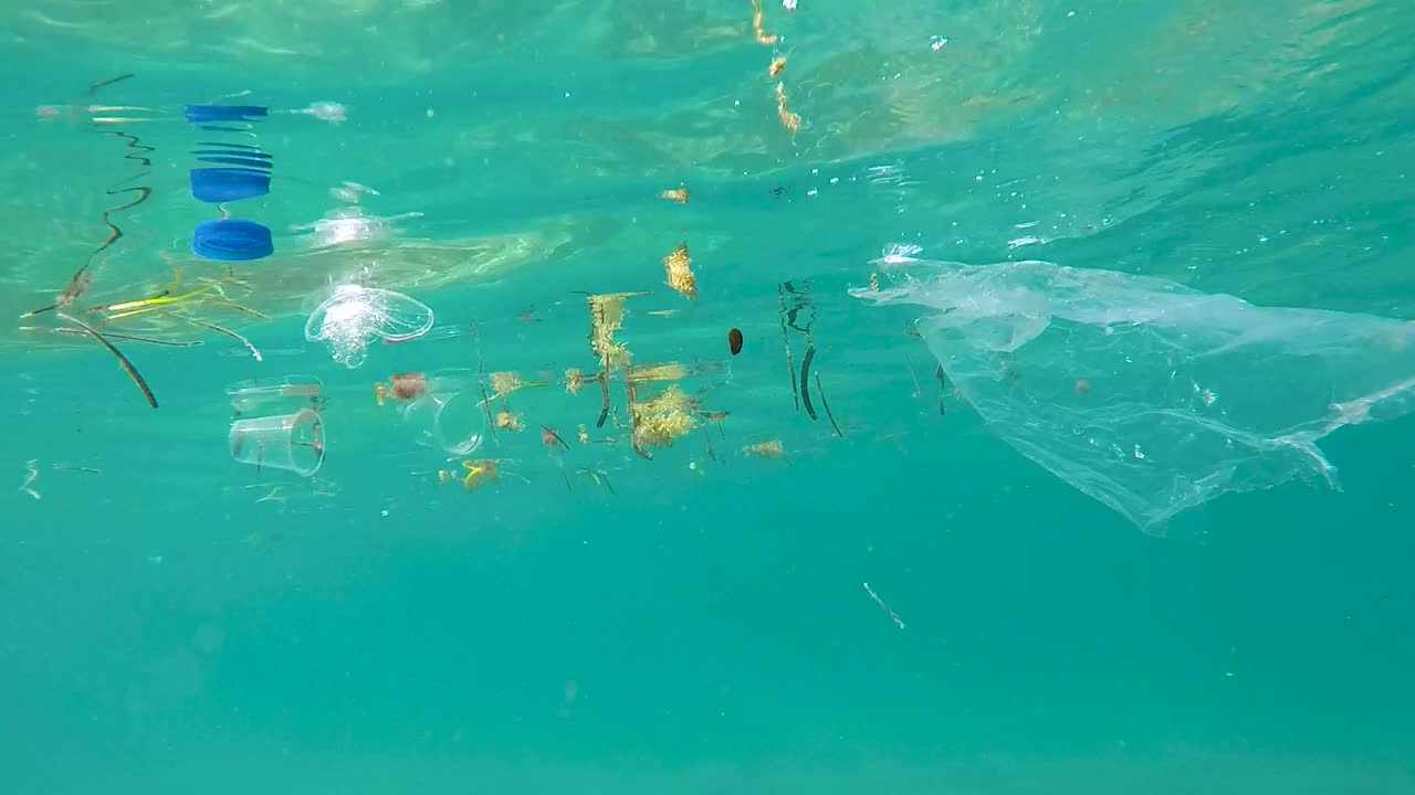 塑料袋，杯子和垃圾漂浮在蓝海的水面上视频素材