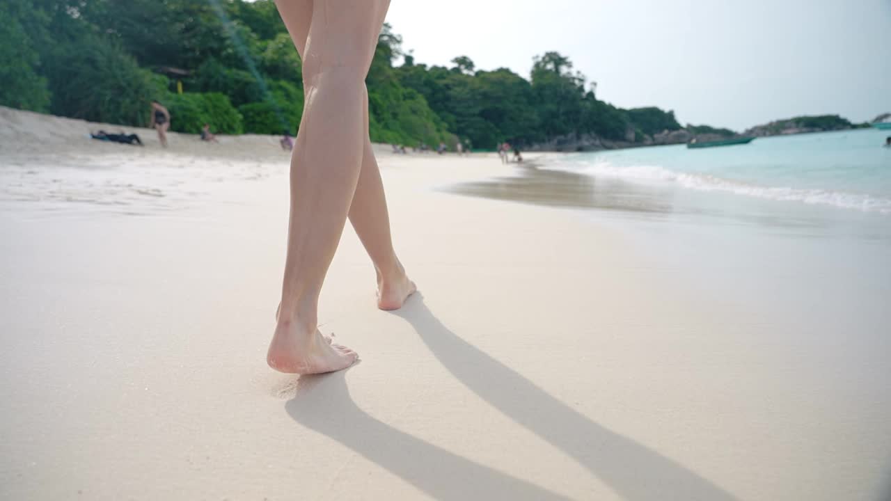 女腿漫步在海岛碧蓝的海水沙滩，浪花飞溅的海浪，热带夏日度假，旅游目的地，跟随女腿漫步在阳光明媚的海岛天堂，享受夏日假期视频素材