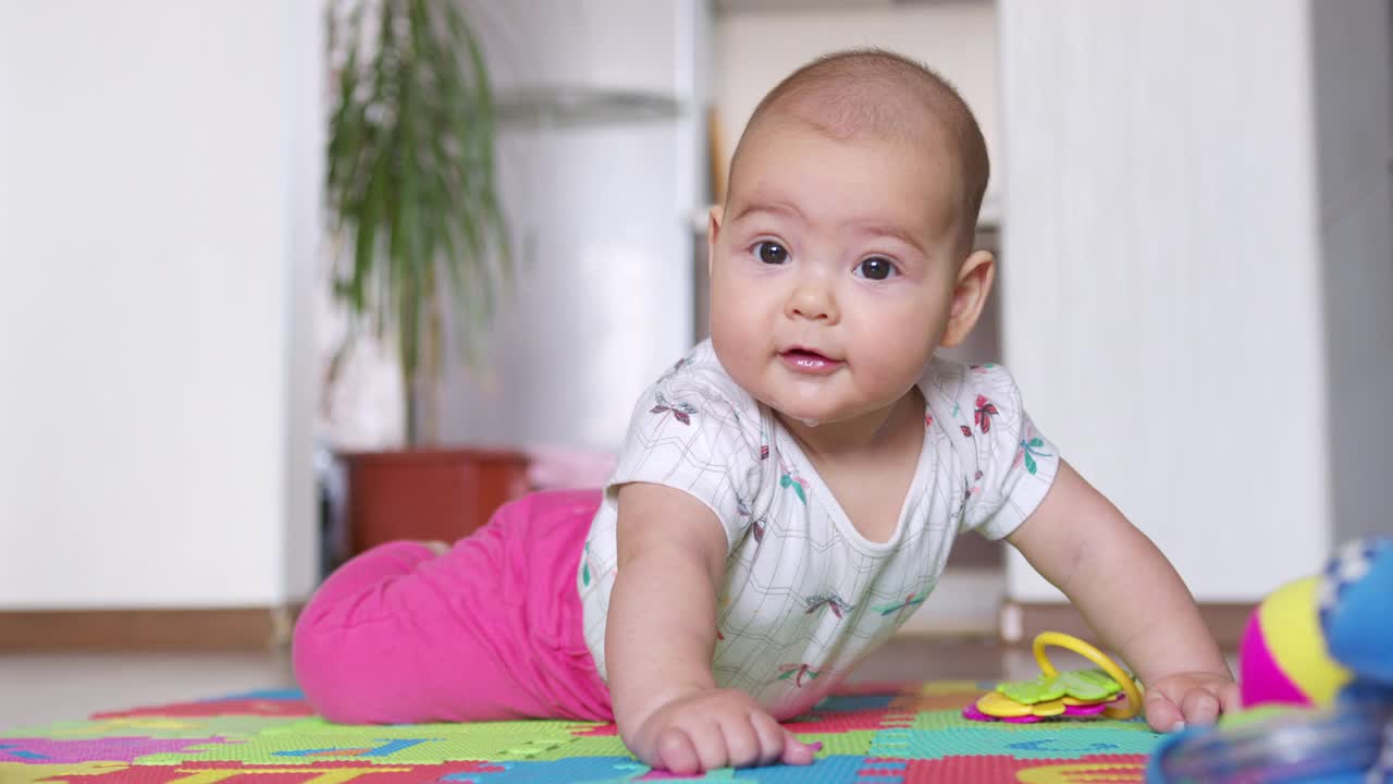 一个漂亮的新生婴儿的肖像，躺在他的肚子上，有趣地看着相机。视频素材