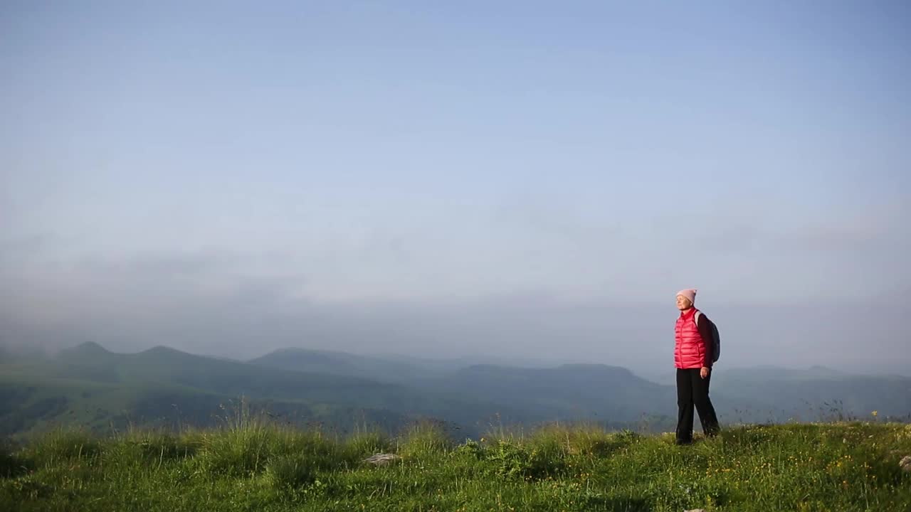 老奶奶背着背包在山区徒步旅行。享受大自然，享受美好时光。视频下载