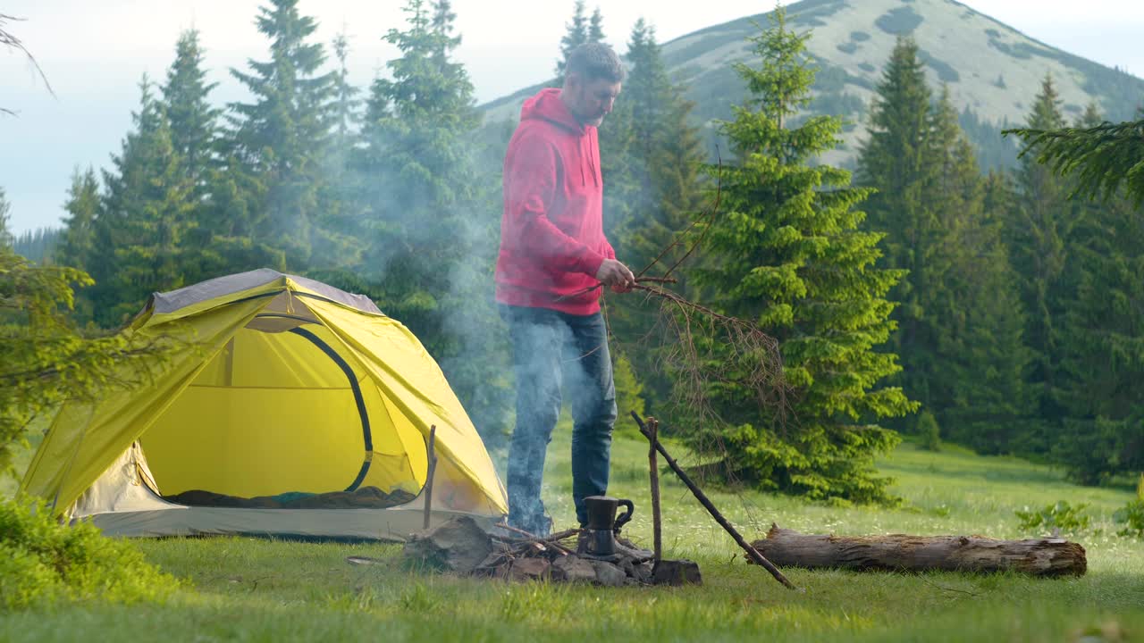 一个长着胡子的男人在山上美丽的森林草坪上点火视频素材