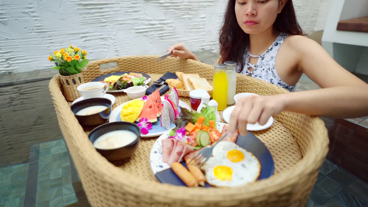 漂浮早餐亚洲女孩在泳池边吃早餐。视频素材