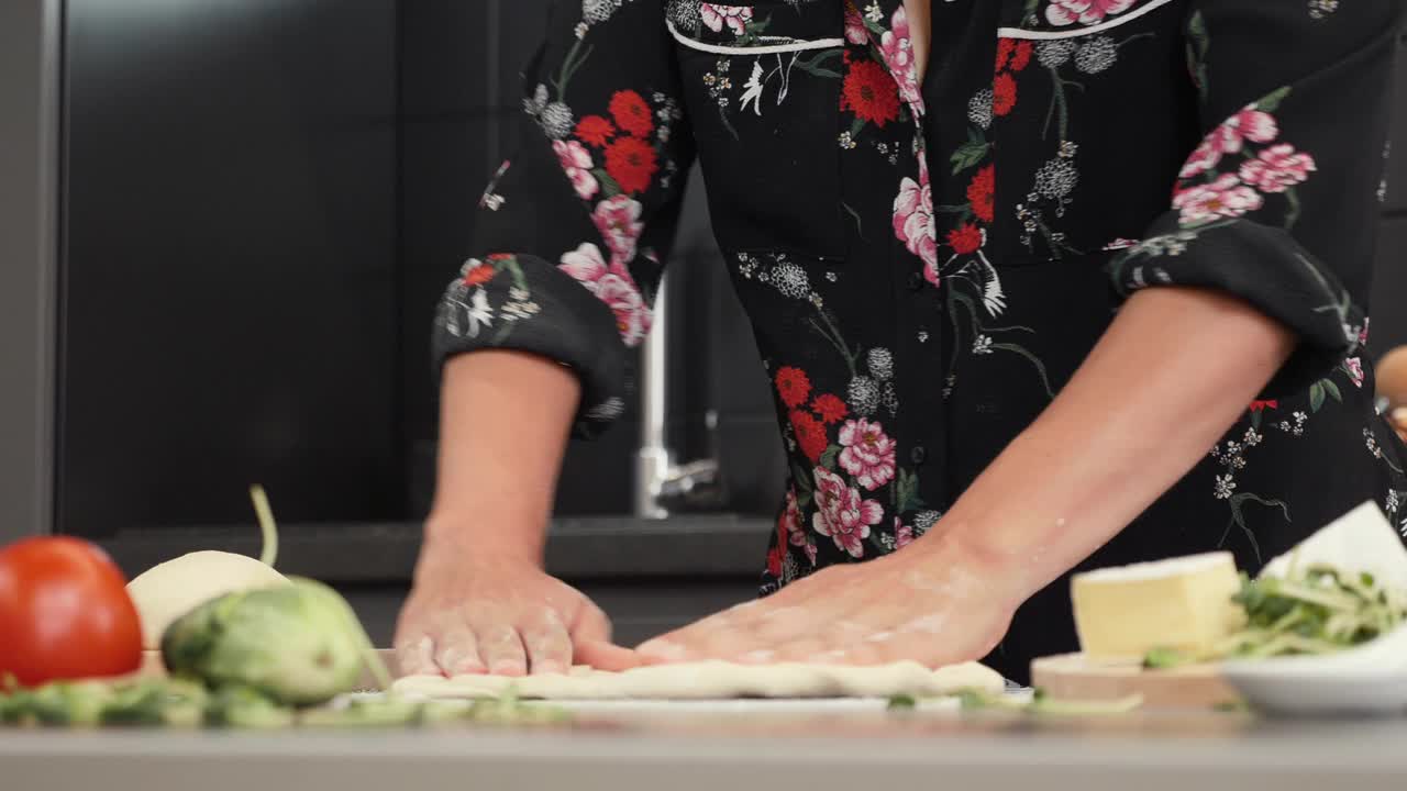 一幅年轻女子用面团做披萨的画像。女性在现代家庭厨房做饭。用传统食谱制作意大利披萨。自制的面包店视频素材