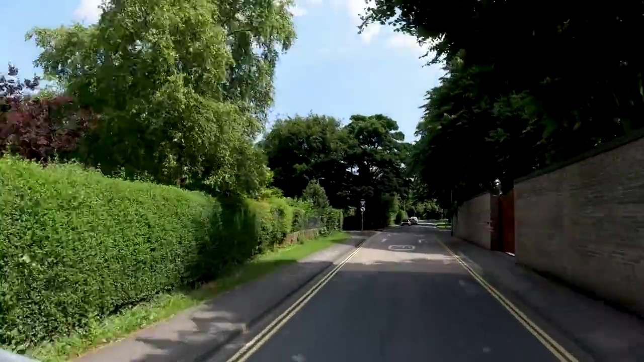 4K POV汽车行驶在漫长的乡村道路通过英格兰村，英国。农场，田野和树篱路在一个阳光灿烂的蓝天。非城市场景的观点视频素材