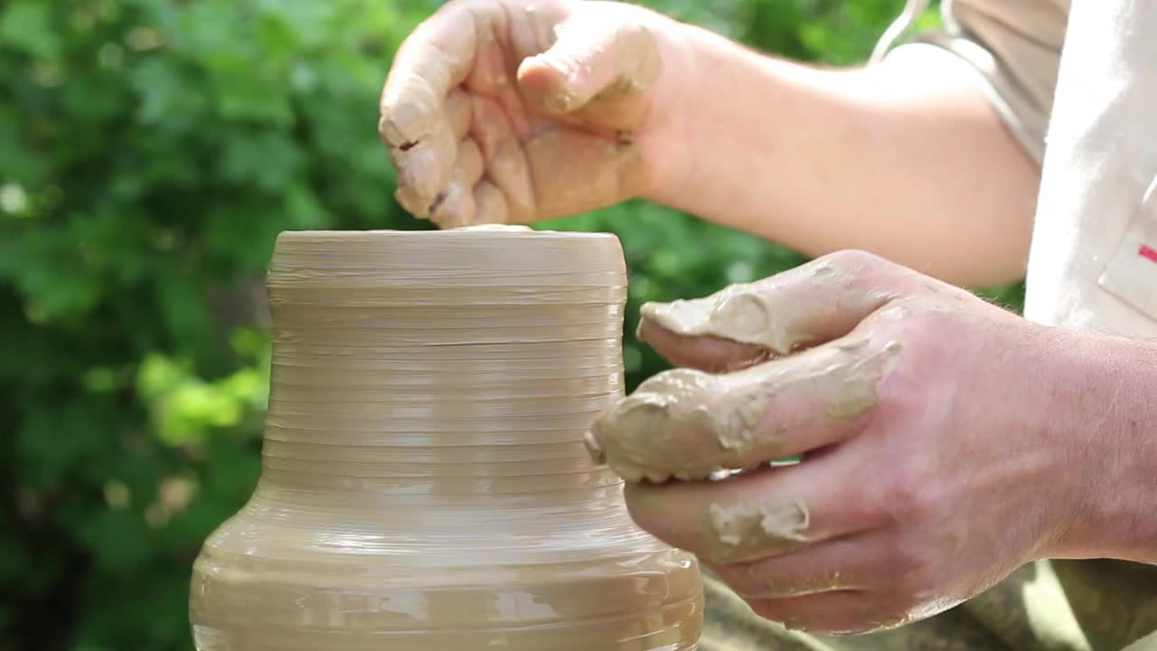 一名白人男性陶工在自动旋转的圆圈上制作陶罐视频素材