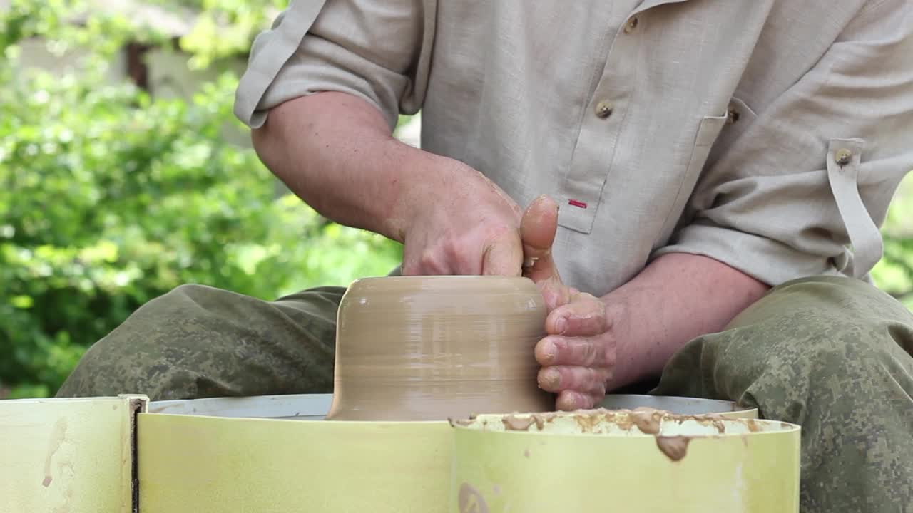 一名白人男性陶工制作棕色陶罐，湿润粘土并绘制模具视频素材