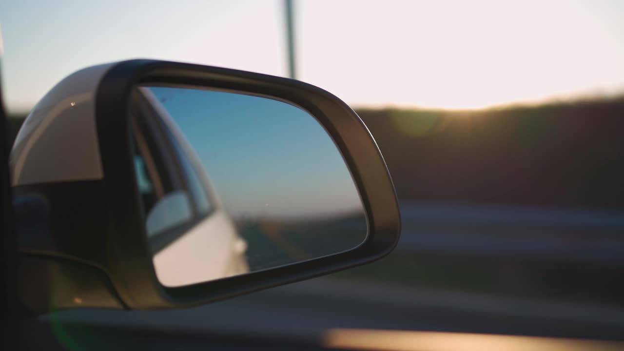 后视镜中的车在夕阳中高速行驶。视频素材