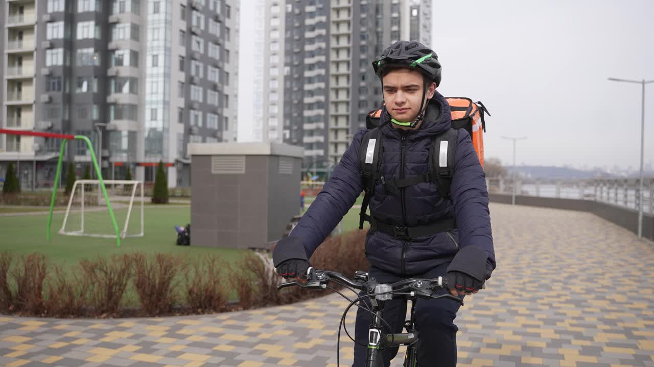 送餐员骑着自行车经过城市操场视频素材