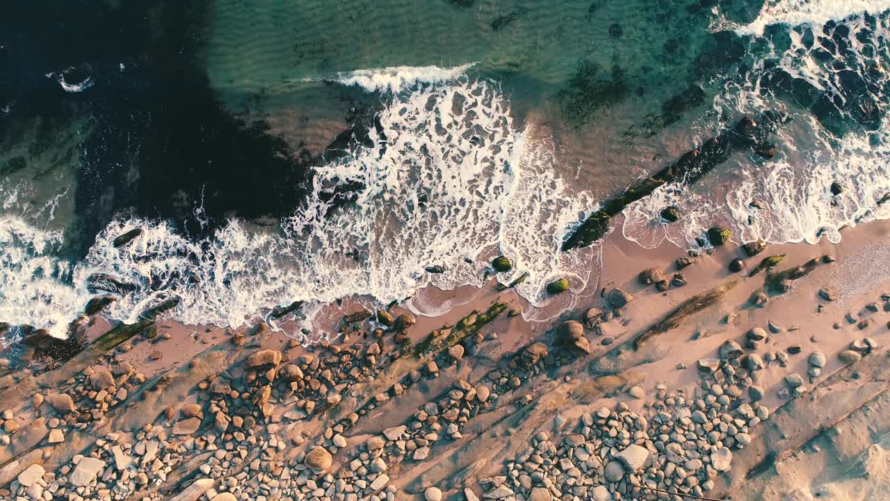 鸟瞰海浪在海滩和岩石海岸上摇摆视频素材