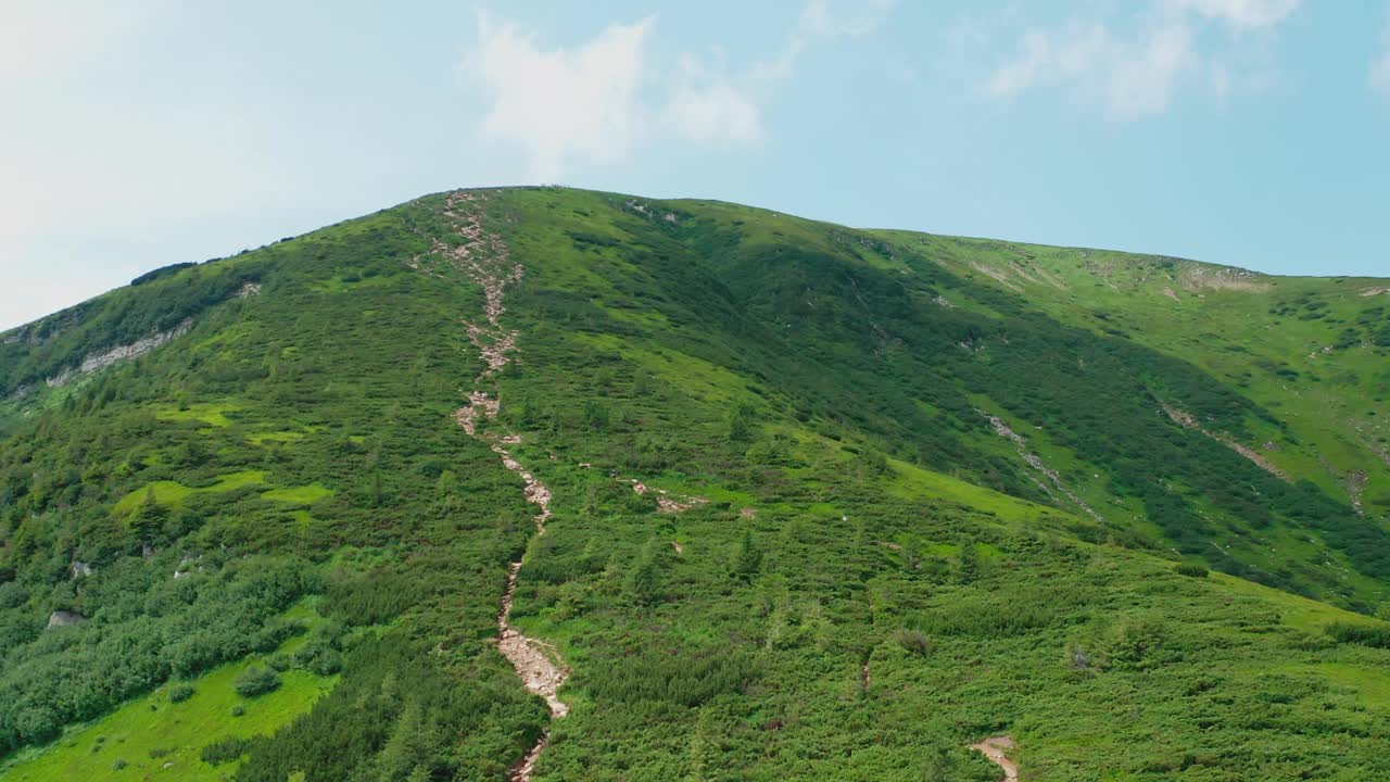 鸟瞰一对年轻夫妇沿着山路走到山顶。视频素材