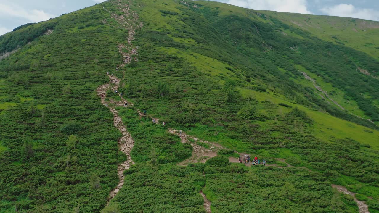 年轻人沿着山路走到山顶的鸟瞰图。视频素材