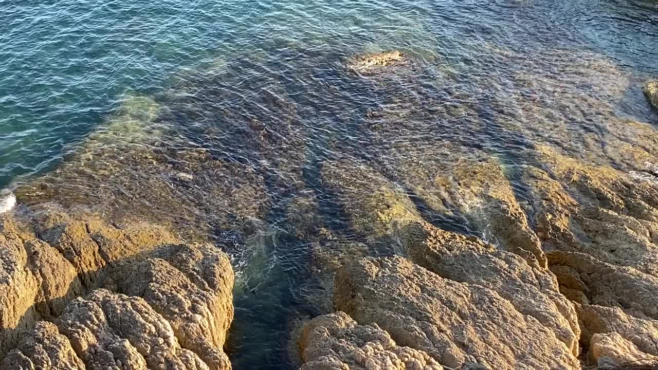 夏日美丽的岩石海岸景观。碧蓝的海水泛起涟漪。视频素材