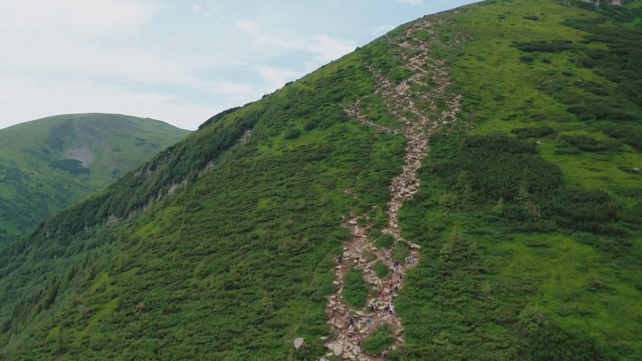 年轻的徒步旅行者沿着山路走到山顶的鸟瞰图。视频素材