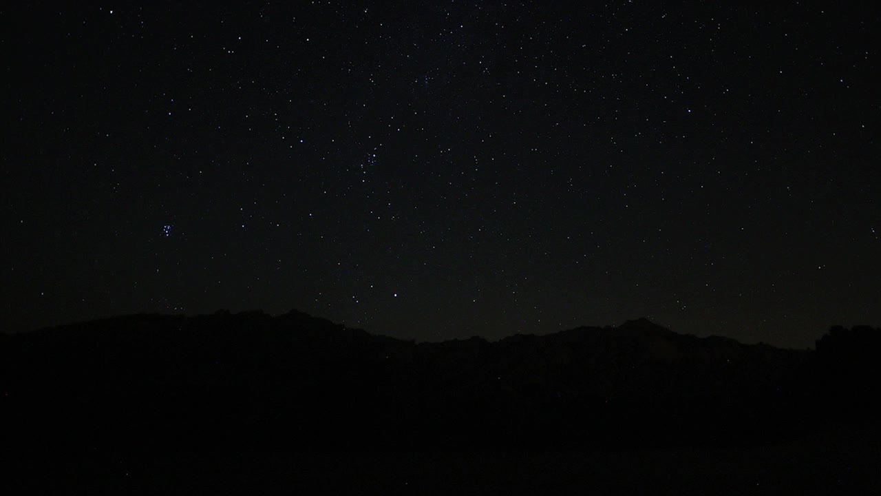 夜空中移动的星迹的时间流逝。以山顶为前景的银河中恒星的景象。夜空自然夏季景观。英仙座流星雨观测。视频素材