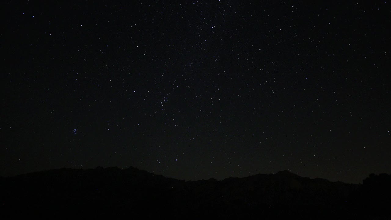 夜空中移动的星迹的时间流逝。以山顶为前景的银河中恒星的景象。夜空自然夏季景观。英仙座流星雨观测。视频素材