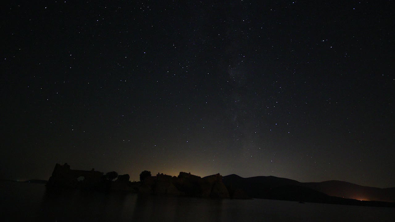 夜空中移动的星迹的时间流逝。以山顶为前景的银河中恒星的景象。夜空自然夏季景观。英仙座流星雨观测。视频素材