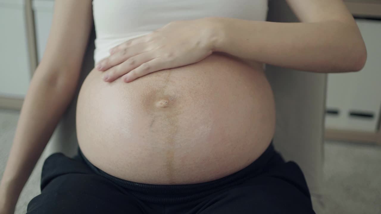 孕妇在家里把润肤霜涂在腹部视频素材