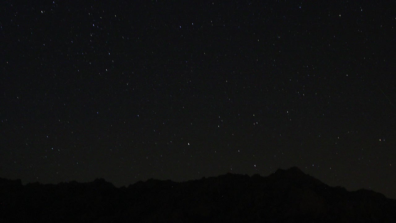 夜空中移动的星迹的时间流逝。以山顶为前景的银河中恒星的景象。夜空自然夏季景观。英仙座流星雨观测。视频素材