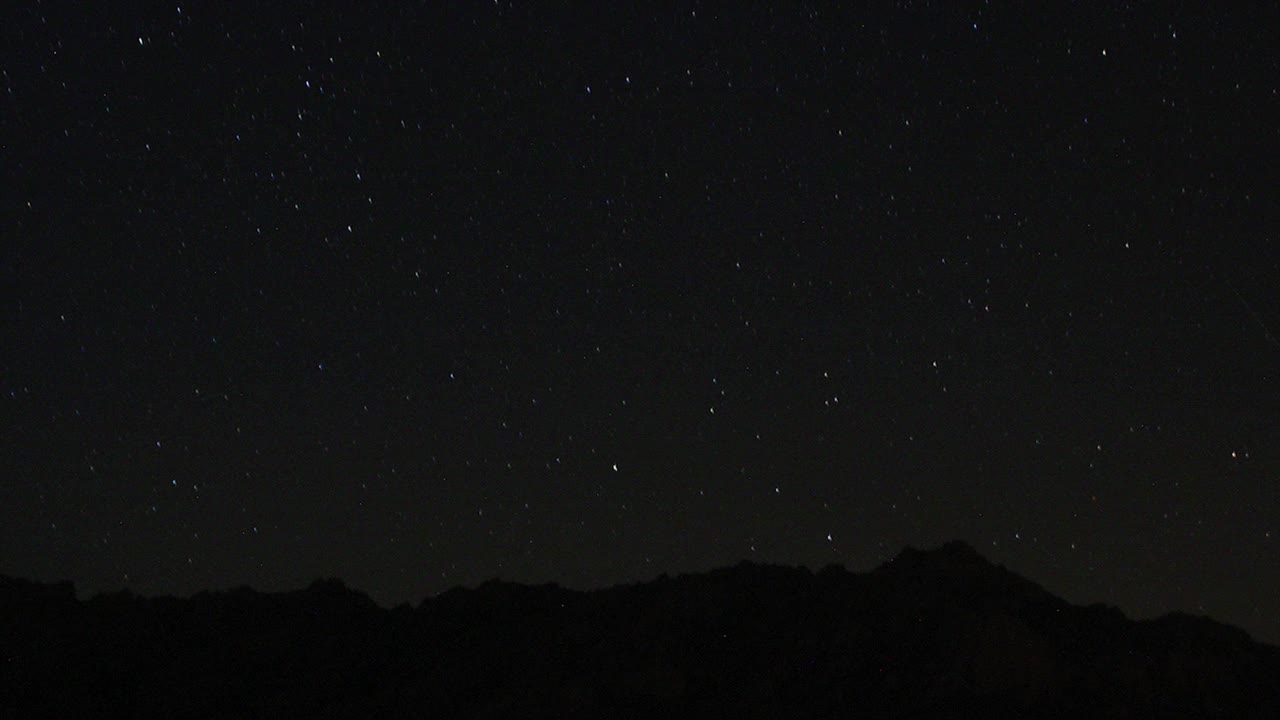 夜空中移动的星迹的时间流逝。以山顶为前景的银河中恒星的景象。夜空自然夏季景观。英仙座流星雨观测。视频素材