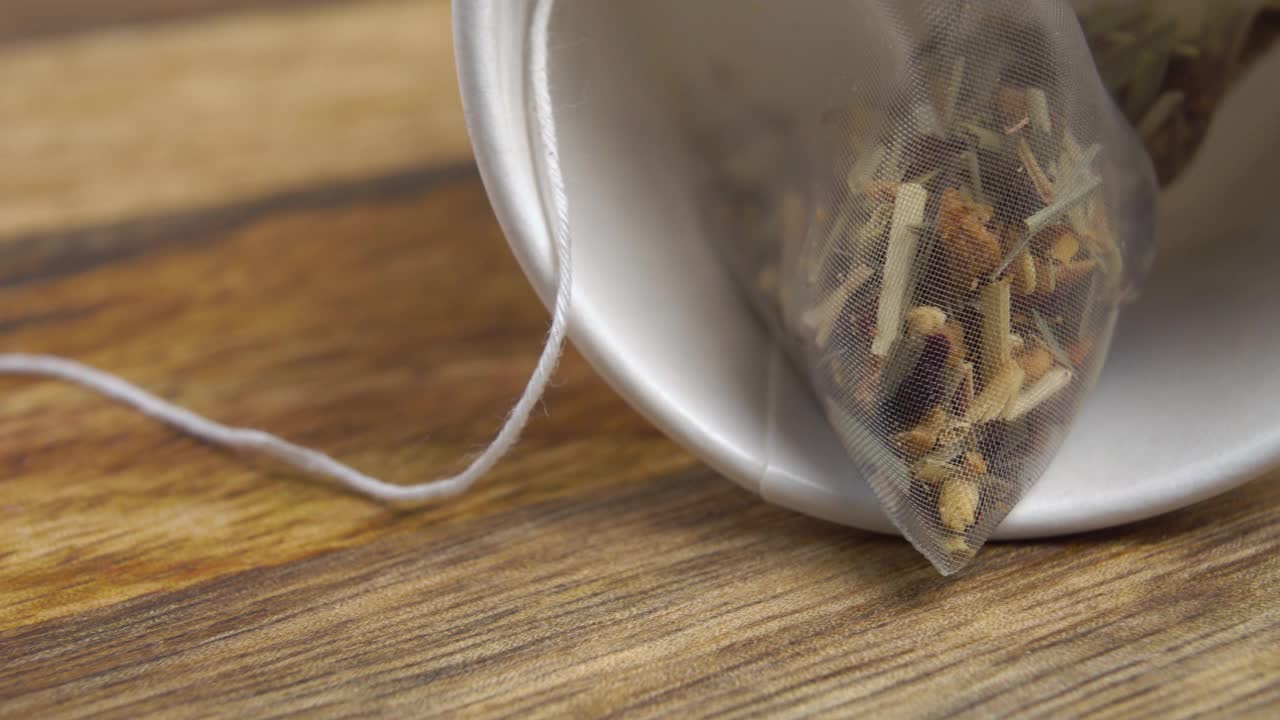 草本花卉水果茶在一个微塑料袋在一个翻倒的白色杯子视频素材