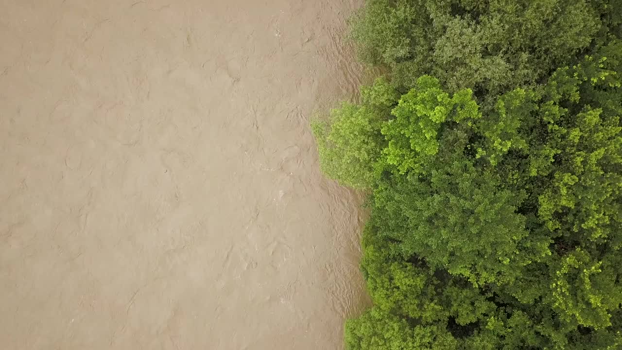 鸟瞰图宽阔的肮脏的河流与泥泞的水在洪水期间在暴雨的春天。视频素材