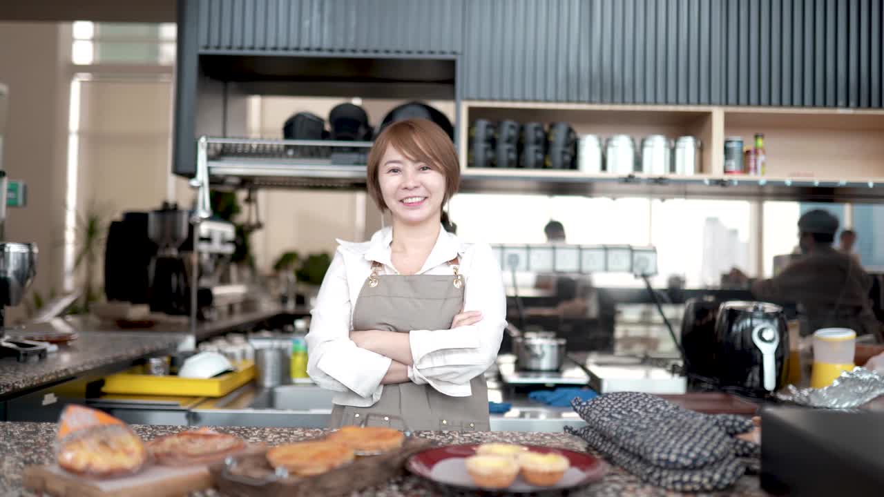 身穿围裙的亚洲华人企业家们一边准备食物一边看着镜头视频素材