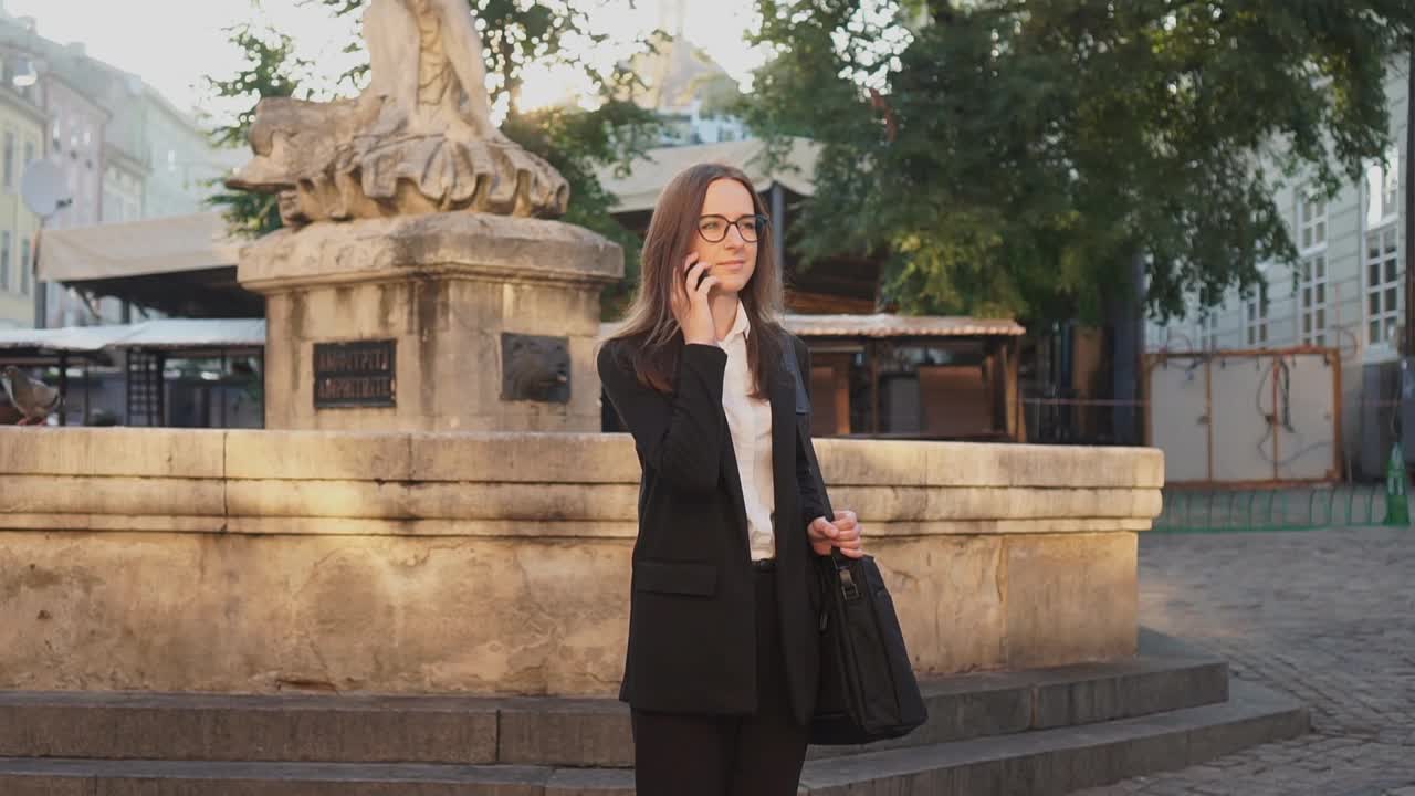 成年白种人自信年轻的商业妇女在白衬衫在老城街讲电话。视频素材