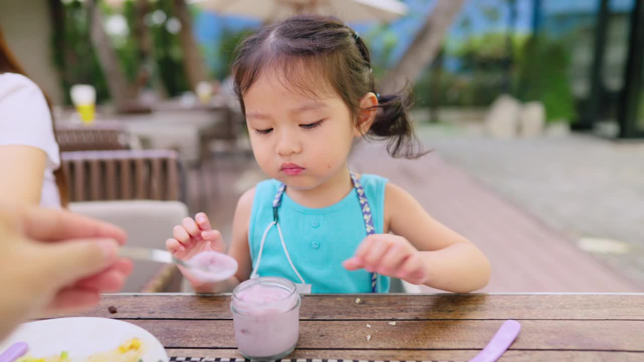 刚学步的小女孩喜欢在假期和爸爸妈妈一起吃早餐视频素材