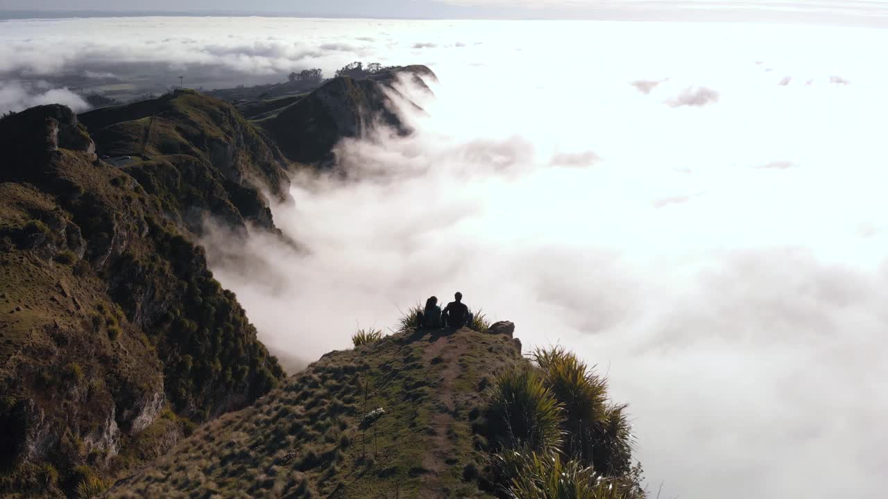 雄伟的雾蒙蒙的早晨，在山峰上，一对夫妇凝视着风景视频素材