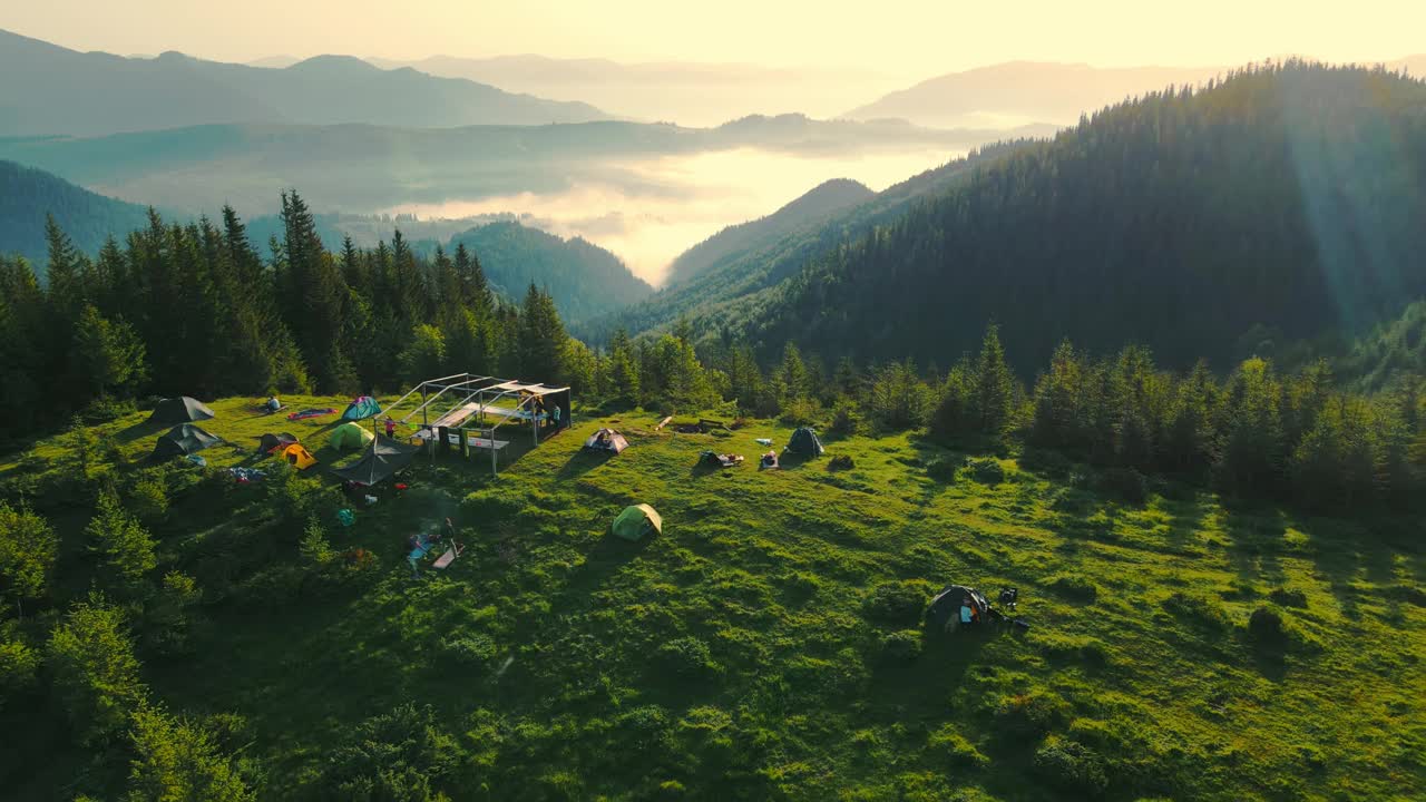 从鸟瞰图上看，在高山上露营。日出时山顶上令人难以置信的风景。山上的晨雾。山上的黎明，日出，雾气和帐篷露营视频素材