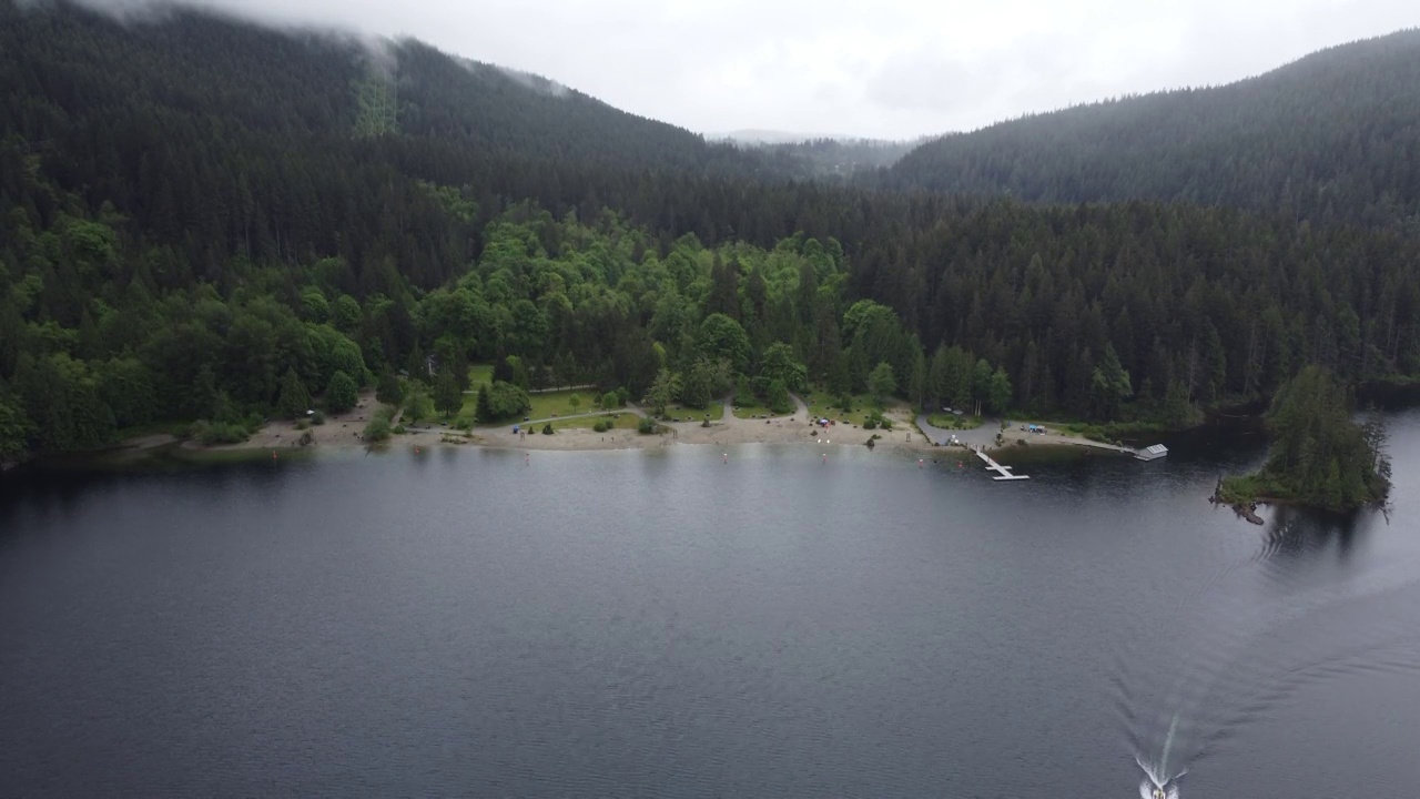 鸟瞰图的湖上的海滩被绿色的森林在一个雨天在加拿大视频素材