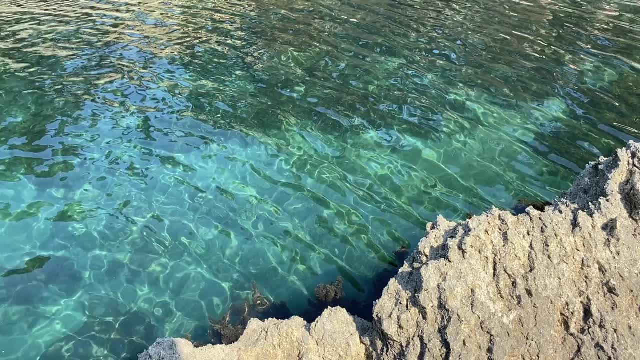 天堂海蓝色泻湖的岩石地中海海岸。碧绿的海水，夏日美妙的海景。晶莹剔透、碧绿翠绿的海水背景。热带海浪。卵石滩。晶莹的蓝绿色透明水。隐蔽的地方视频素材