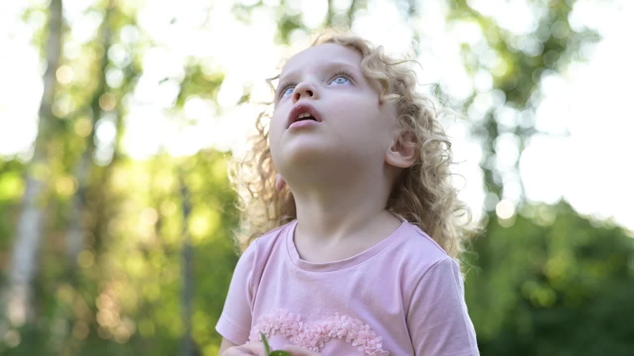 一个美丽的卷发小女孩的肖像，她望着天空视频素材