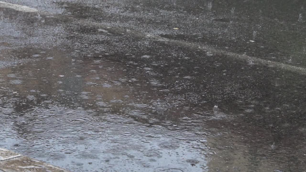 秋天的雨水落在柏油路上，形成大水坑，淹没了街道。视频素材