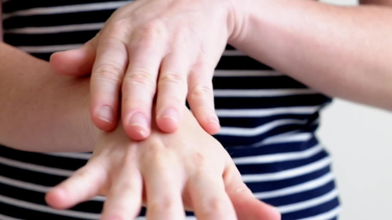 一位年轻女子双手涂护手霜，双手按摩视频素材