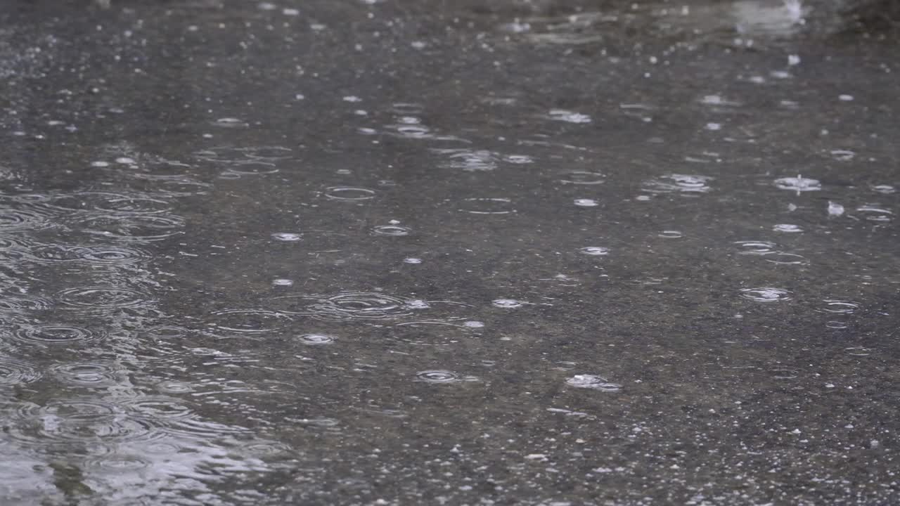 雨点落在柏油路上的水坑里。雨点落在路上。由于大雨，道路被淹了视频素材