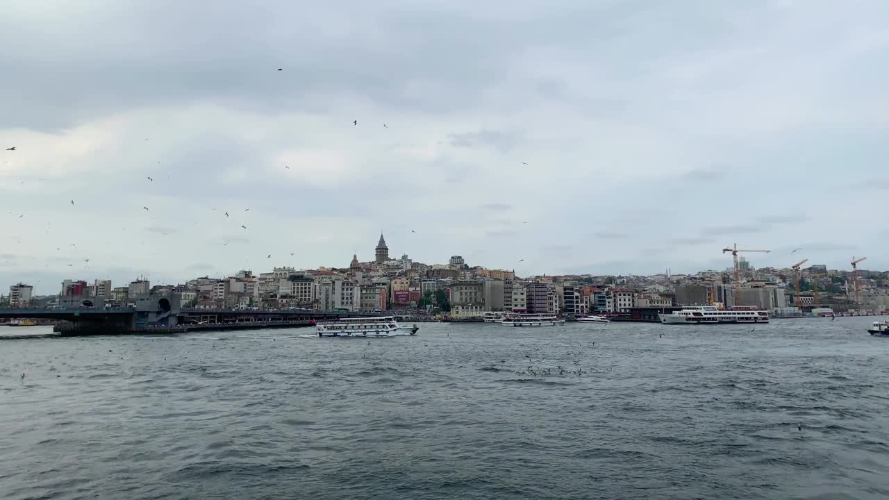 游船驶过，海鸥在博斯普鲁斯海峡的金角区飞翔。加拉塔桥，卡拉科伊和Beyoglu地区都在伊斯坦布尔的视野中。美丽的景色。视频素材