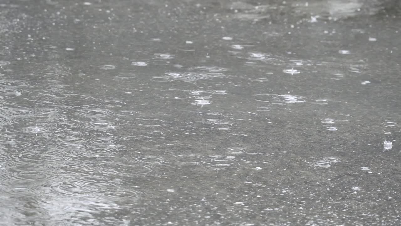 雨点落在柏油路上的水坑里。雨点落在路上。由于大雨，道路被淹了视频素材