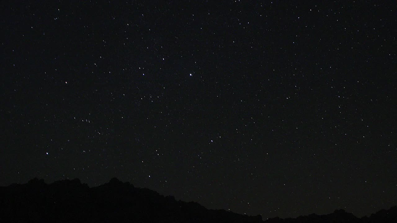 夜空中移动的星迹的时间流逝。以山顶为前景的银河中恒星的景象。夜空自然夏季景观。英仙座流星雨观测。视频素材