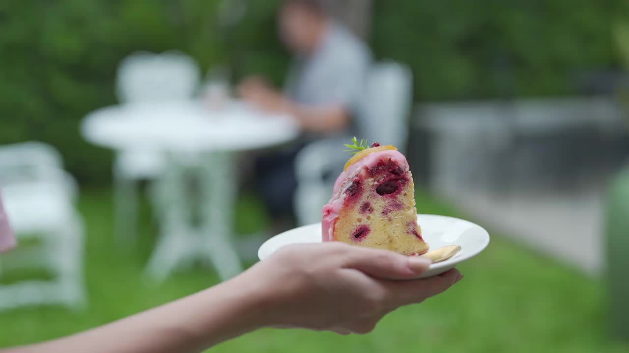 女服务员在花园里给男顾客端冰饮料和蛋糕视频素材