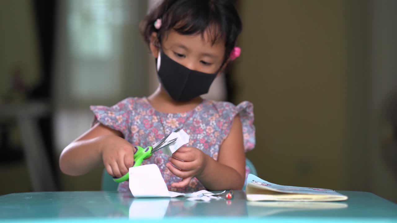 女孩在餐桌上学习使用剪刀。视频素材