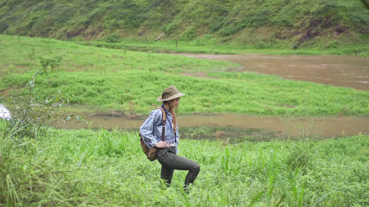 4K亚洲女性背包客在小溪边的山路上徒步旅行视频素材