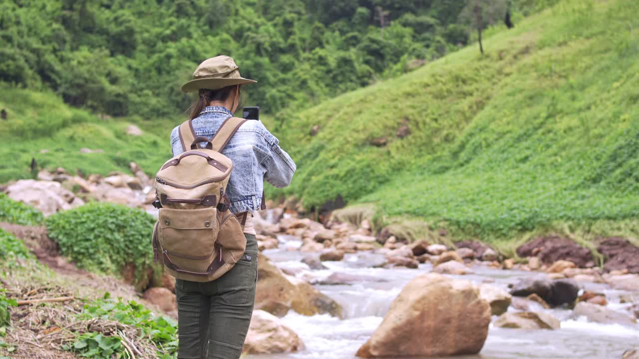 4K亚洲女性背包客在小溪边的山路上徒步旅行视频素材