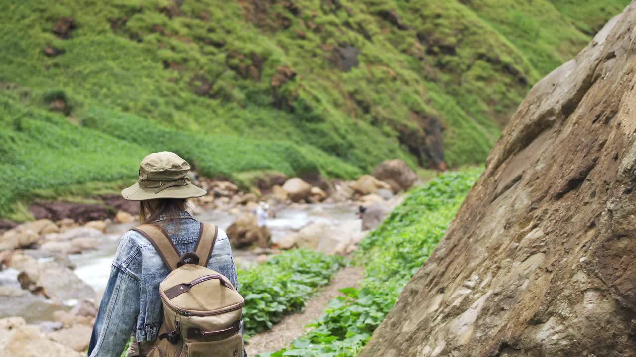 4K亚洲女性背包客在小溪边的山路上徒步旅行视频素材