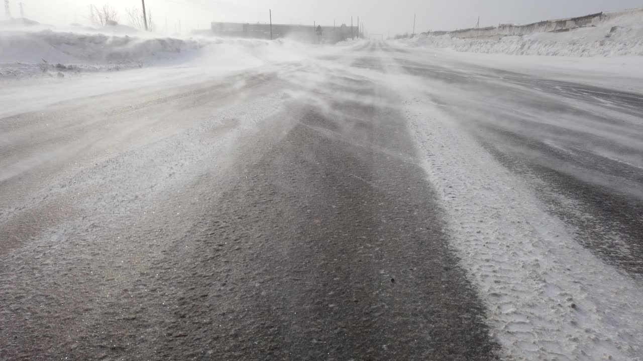 风把雪吹过马路。冬天的暴风雪。雪堆关闭视频素材